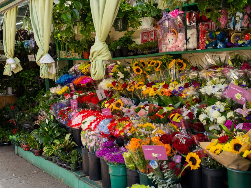 A vibrant display of flower bouquets outside a florist shop, showcasing a variety of fresh flowers including sunflowers, roses, tulips, and chrysanthemums in different colors such as yellow, red, pink